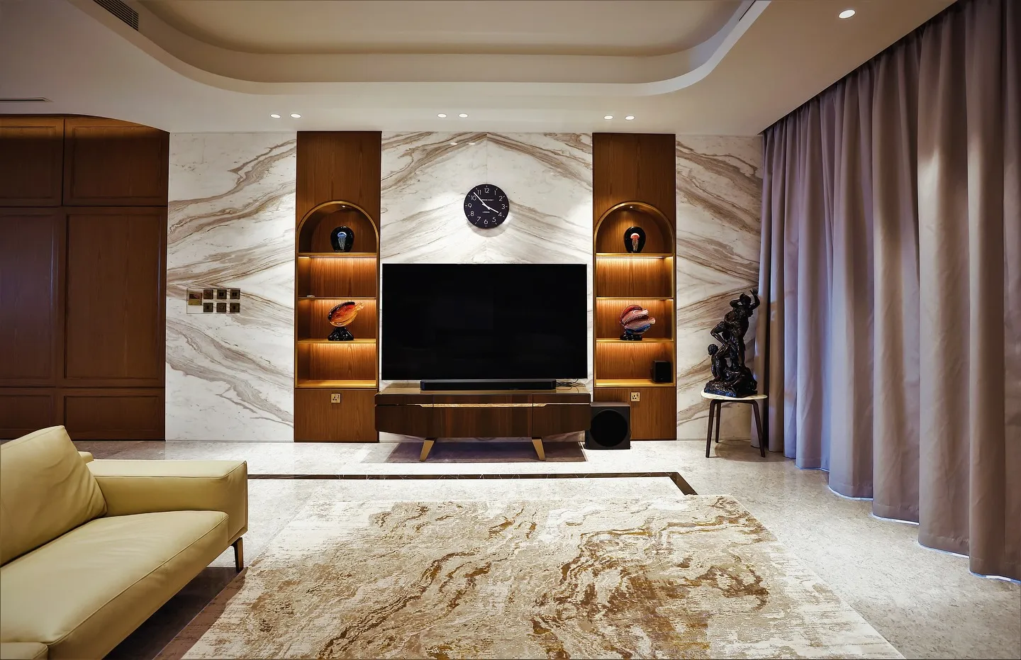 A cozy living room featuring a sleek marble wall and a modern television, creating a stylish and inviting atmosphere.