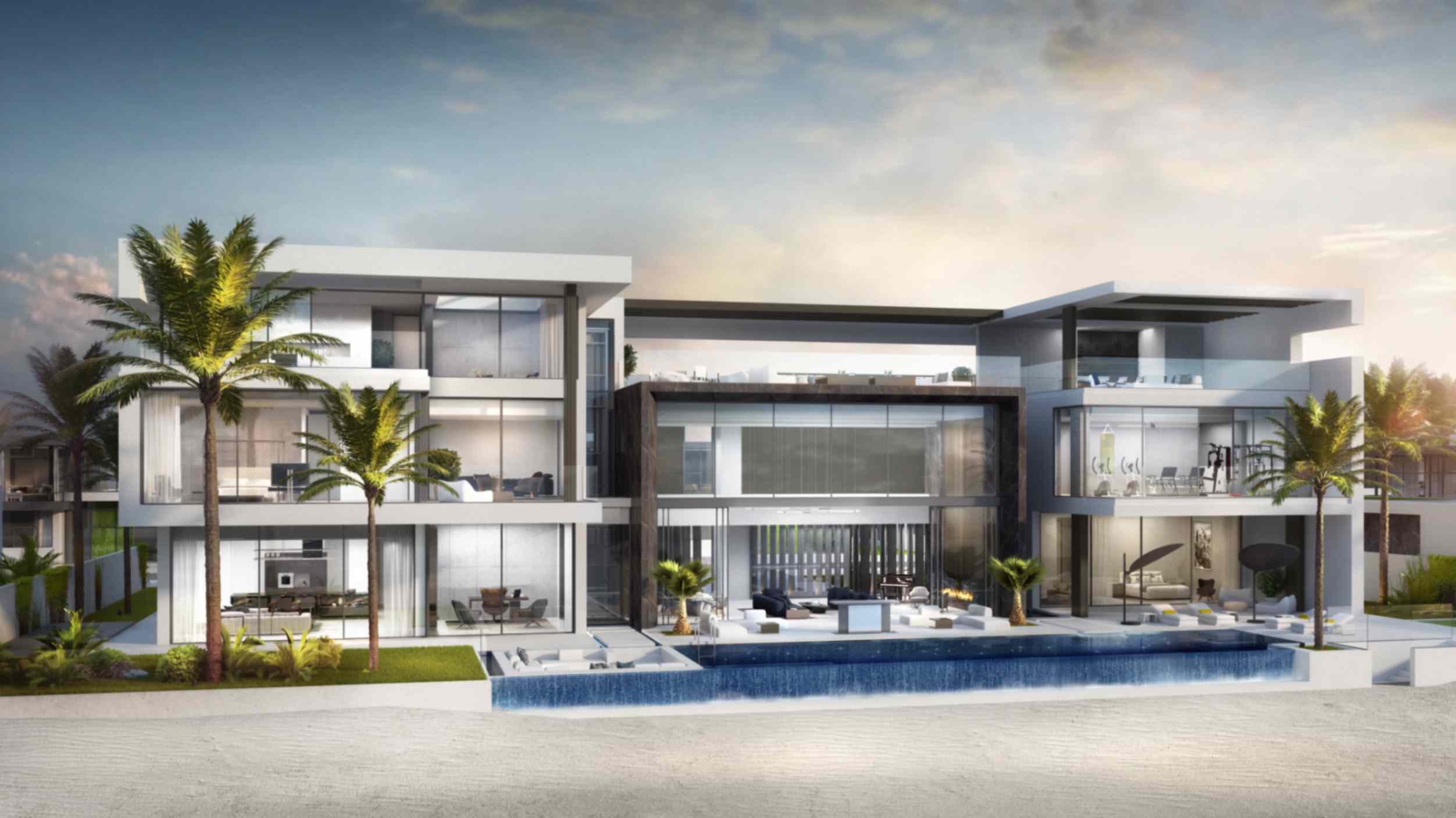 Modern beachfront mansion with large glass windows, balconies, and a pool in front, surrounded by palm trees, under a partly cloudy sky.