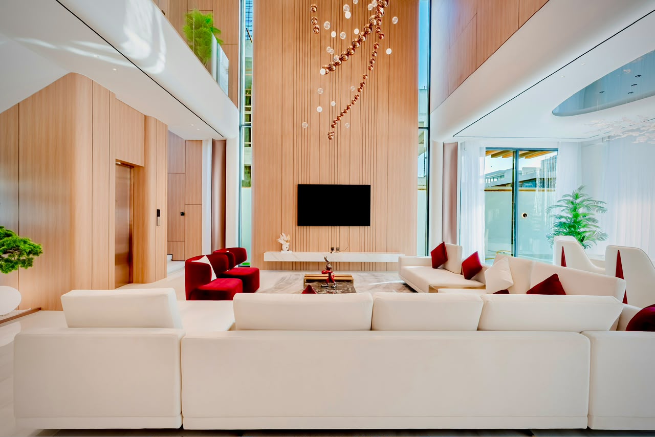 Modern living room with a large sectional sofa, circular coffee tables, a rug with blue accents, and a marble bar area in the background.